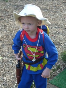 Boy Twin practicing his cowboy walk, wearing superhero pajamas and a Dr. Seuss backpack.